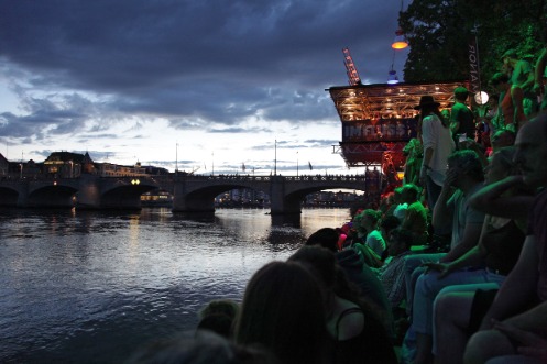 Zuschauer am Rhein lauschen in der Abenddämmerung Musik vom Kulturfloss
